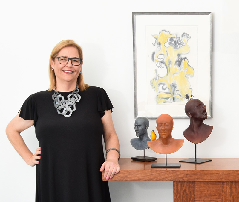 Christine Carlson Beirne, Concierge Services Liaison standing next to some glass head sculptures.